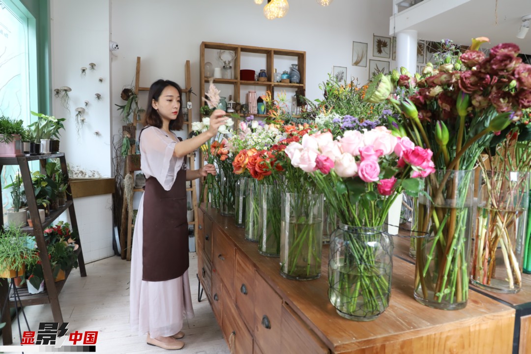 王黎媛是一名河南姑娘，在昆明念完大學(xué)后，就再也舍不下春城的藍(lán)天陽光、青山碧水，更舍不下這里的四時(shí)繁花，于是就干脆留了下來，成了一名媒體人。2017年的時(shí)候又毅然辭去工作，創(chuàng)業(yè)開起了花店，成了都市里的一名“花房姑娘”。圖為王黎媛在自己的花店中整理鮮花。新華網(wǎng) 周亞平/攝 念新洪/文